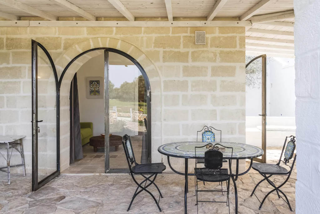 Patio privato in pietra Masseria Luxury Itria Ostuni Patio privato in pietra con tavolo e porte ad arco di una masseria a Ostuni vicino al mare